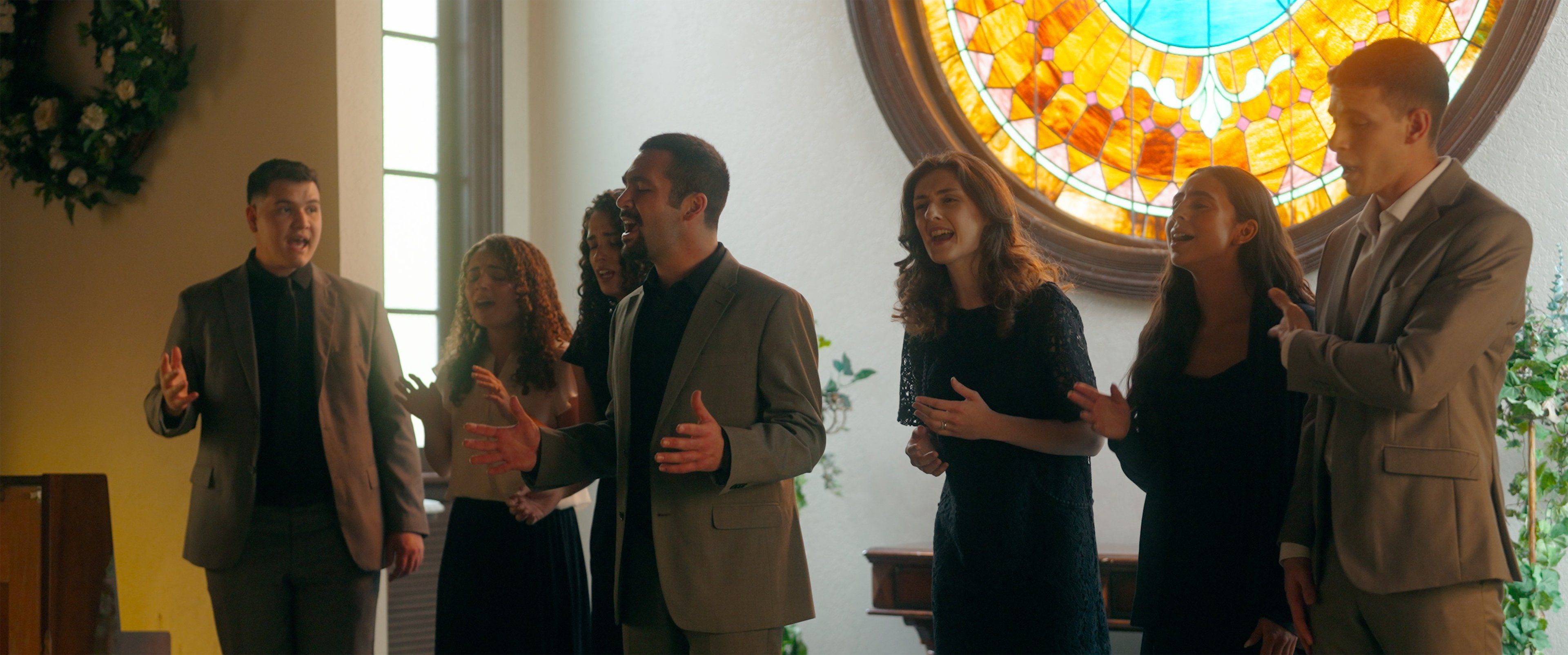 Abrigo Vocal singing inside a church beneath a round stained-glass window